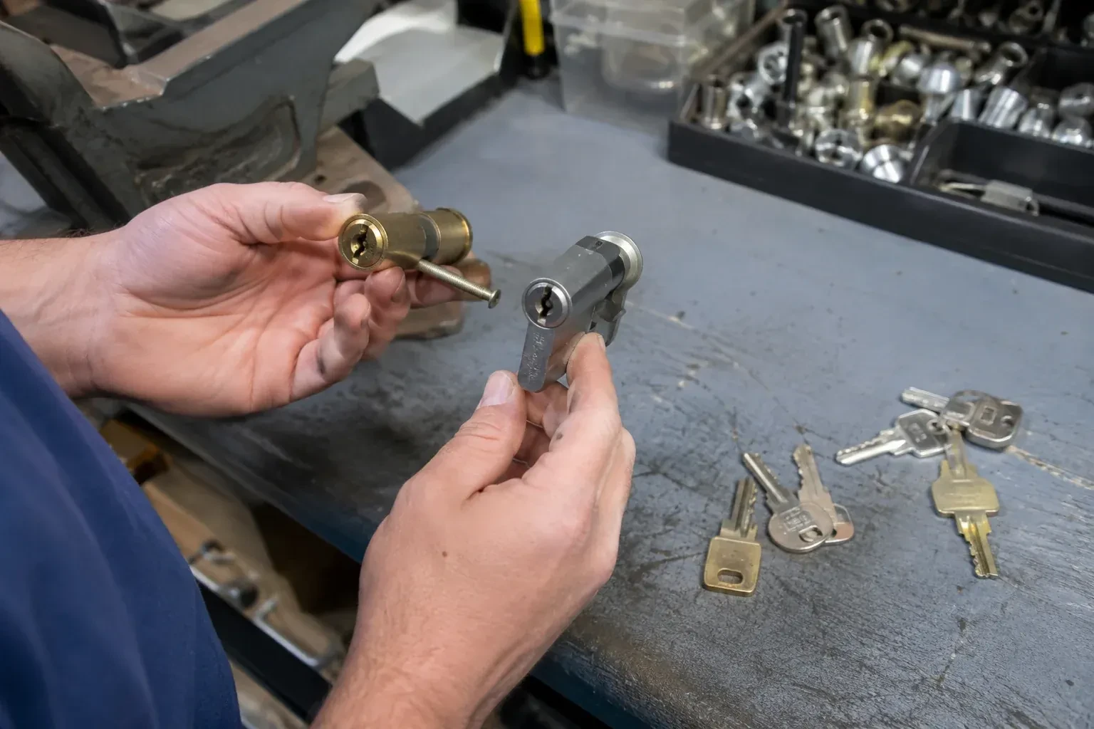 Hands comparing detached lock cylinders beside loose keys on a workbench. — Broken Key Extraction, Kitchener